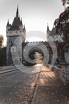 Morning sun shining through trees with warm glow and gate of Vajdahunyad castle in Budapest city park