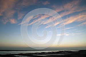 Morning sunrise over body of water with cloudy sky