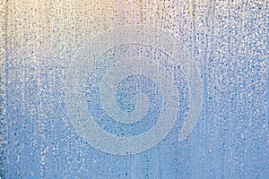 Morning sunrise through the raindrops on the glass. Condensation on Windows in the cold. Texture of the water