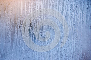 Morning sunrise through the raindrops on the glass. Condensation on Windows in the cold. Texture of the water
