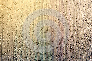 Morning sunrise through the raindrops on the glass. Condensation on Windows in the cold. Texture of the water