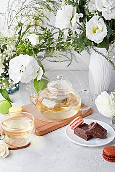 Morning table setting. Green tea, macaroon desserts, chocolate, white flowers - time for yourself, enjoy your time
