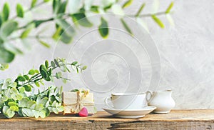 Morning tea in white cup, branches with leaves, gift box