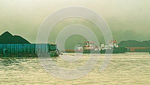 Morning traffic at Mahakam River, Samarinda.  Tugboat towing huge barge loaded by black coal at Mahakam River