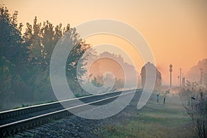 Morning train passing in the autumn haze at sunrise light