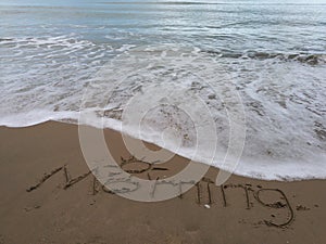 MORNING WORD DRAW ON THE BEACH SAND.