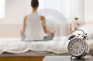 Morning yoga. Alarm clock standing on bedside table