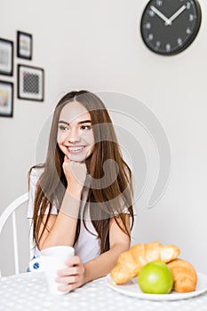 Morning of young woman with breakfast in kitchen at home