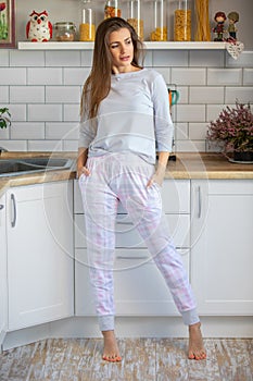 Morning young woman in pajama in modern house kitchen, happy and smiling