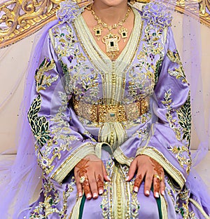 A Moroccan bride sits on the wedding chair in the traditional Moroccan dress. The caftan photo