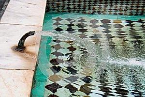 Moroccan fountain at the Ben Youssef Madrasa in Marrakech covered in small colorful tiles