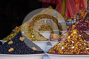 Moroccan local market with a stall of different types of olives and bottles of olive oil