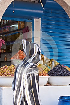 Moroccan local market with a stall of different types of olives and bottles of olive oil