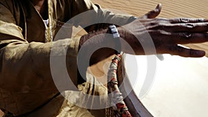 A Moroccan man plays a traditional djembe drum in the desert.