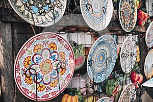 Moroccan plates hanging on an outside display rack with fruit wall decors, for sale at a flea market