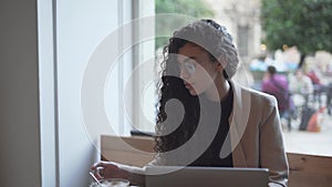 Moroccan Woman At Cafeteria Stirring Coffee While Looking At Laptop Computer. - close up
