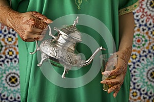 Moroccan woman with henna painted hands pouring tea