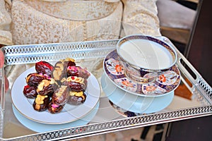 Moroccan woman in pink kaftan. She holds a cup of milk and dates in her hands, to present them to the newlyweds.