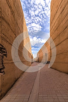 Morocco, Fez, view over a narrow empty street with left and right yellow buildings and lantern poles, and occasionally in the dist