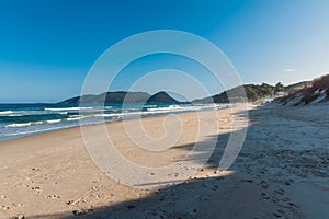 Morro das Pedras beach with waves. Sandy coastline with sky and sun light in Brazil photo
