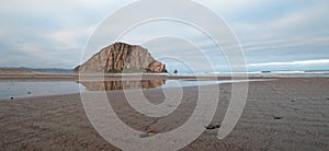 Morro Rock at sunrise under cumulus clouds at Morro Bay State Park camping spot on the Central California Coast USA