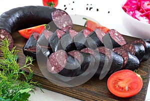 Morsilla - blood sausage. Pieces of Spanish black pudding on a wooden cutting board on white background. Easter menu