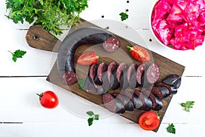 Morsilla - blood sausage. Pieces of Spanish black pudding on a wooden cutting board on white background. Easter menu