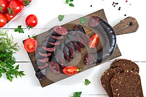 Morsilla - blood sausage. Pieces of Spanish black pudding on a wooden cutting board on white background. Easter menu. The top view