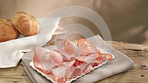 mortadella on a white plate. italian sausage on a wooden table with bread.