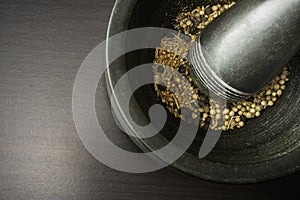 Mortal and pestle withspices on black wooden background