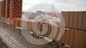 Mortar on a brick during the construction of a house. Construction site of a new house in summer, man working with brick and