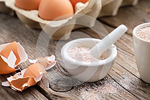 Mortar of crushed eggshell, cardboard box of eggs. Whole and powdered eggshells, natural calcium.