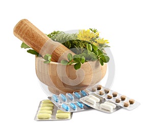 Mortar with fresh green herbs and pills on white background