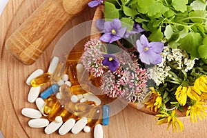 Mortar with fresh herbs and pills on wooden board, flat lay