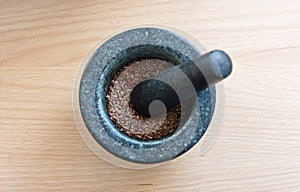 A mortar full of linseed / flaxseed with a pestle on top