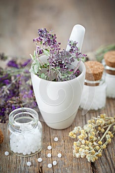 Mortar of healing herbs and bottles of homeopathic globules.