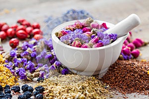 Mortar of healing herbs, herbal tea assortment and dry berries