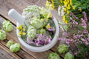 Mortar of medicinal herbs, healthy plants on wooden table. Top view. Herbal medicine. photo