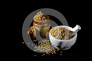 Coriander Powder and seeds with mortar and pestle on black background