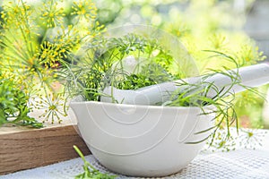 Mortar and pestle with fresh green herbs spices. Fresh dill, parsley, arugula and garlic on wooden board and white towel