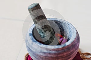 A mortar and pestle or lesung batu in Malay with crushed chilies, fried shallots and shrimp paste mixed together.