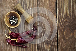 Mortar and pestle with pepper and spices on wooden table