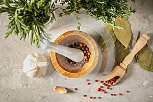 Mortar with pestle, spices and herbs on table, top view