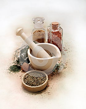 Mortar and pestle with spices and herbs on white table cloth