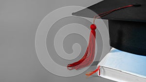 A mortarboard on an isolate gray background with empty copy space to the left. Stock photo