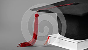 A mortarboard on an isolate gray background with empty copy space to the left. Stock photo