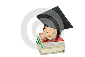 Mortarboard and piggy bank on stack book isolate on white background