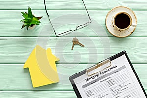 Mortgage application with coffee, glasses, house figure and keys on mint green wooden background top view