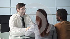 Mortgage broker and diverse couple handshaking ready to make deal