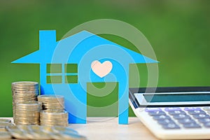 Mortgage calculator, Blue house model and stack of coins money on natural green background,Interest rates and Banking concept